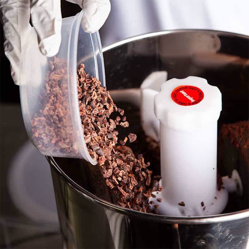 pouring cocoa nibs to make a paste