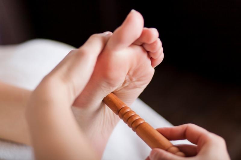 therapist using a reflexology stick on a foot